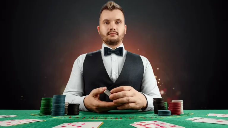 Male casino dealer holding a pack of cards.